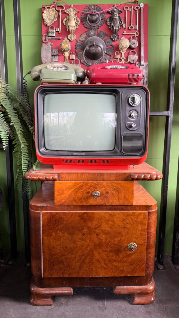 Retro TV with vintage phones on a wooden cabinet, exuding classic charm.